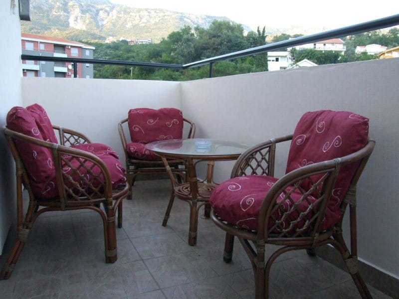 Ugodan balkon s ratan nameštajem i pogledom na planine u kući u Bečićima, Crna Gora.