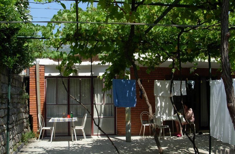 Ugodna terasa kuće u Bečićima, Crna Gora: ciglena obloga, trpezarijski deo pod nadstrešnicom od vinove loze.