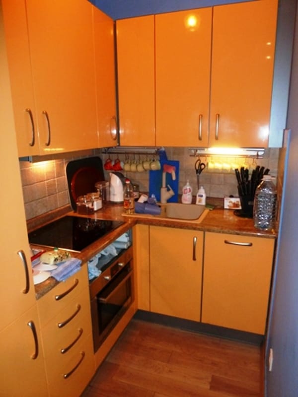 Compact kitchen with orange glossy fronts in an apartment, Risan, Montenegro: built-in appliances and sink.