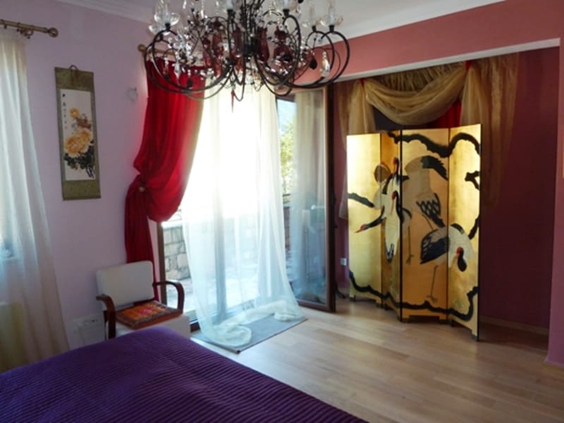 Bedroom in an apartment in Risan, Montenegro: a purple bed, a wrought-iron chandelier, a screen with cranes, and access to the balcony.