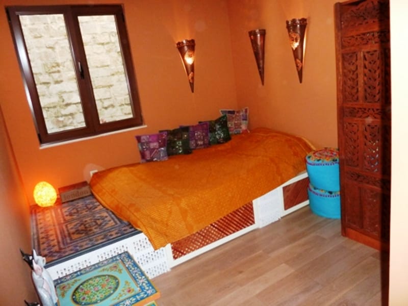 Bedroom in an oriental style in an apartment in Risan, Montenegro: a bed with an orange bedspread and a carved wooden screen.