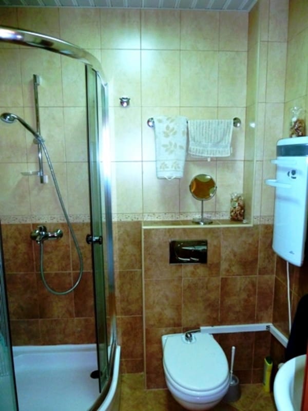 Bathroom in an apartment in Risan, Montenegro: shower cabin, wall-mounted toilet, and beige tile interior.