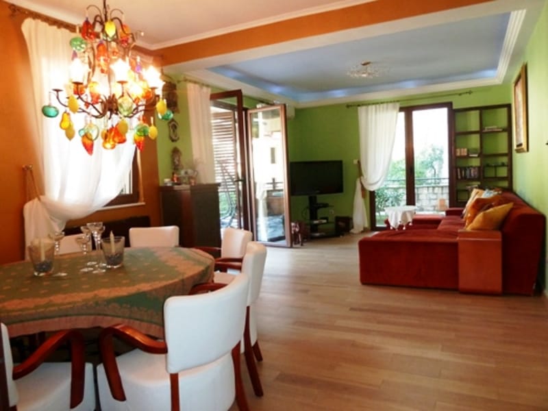 Living room with dining area in an apartment in Risan, Montenegro: bright interior, colorful chandelier, red sofa, and terrace.
