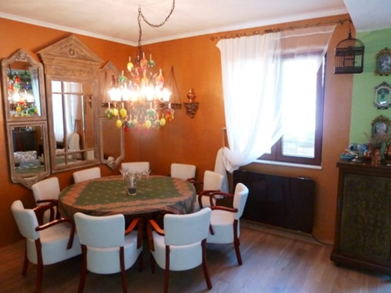 Living room interior with dining area in an apartment, Risan, Montenegro: round table, white chairs, and a vintage chandelier.