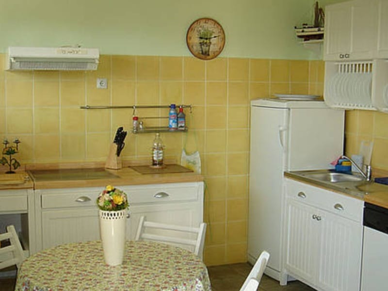 Bright kitchen with white cabinetry and yellow tile in a villa in Shushan, Montenegro: dining area and appliances.