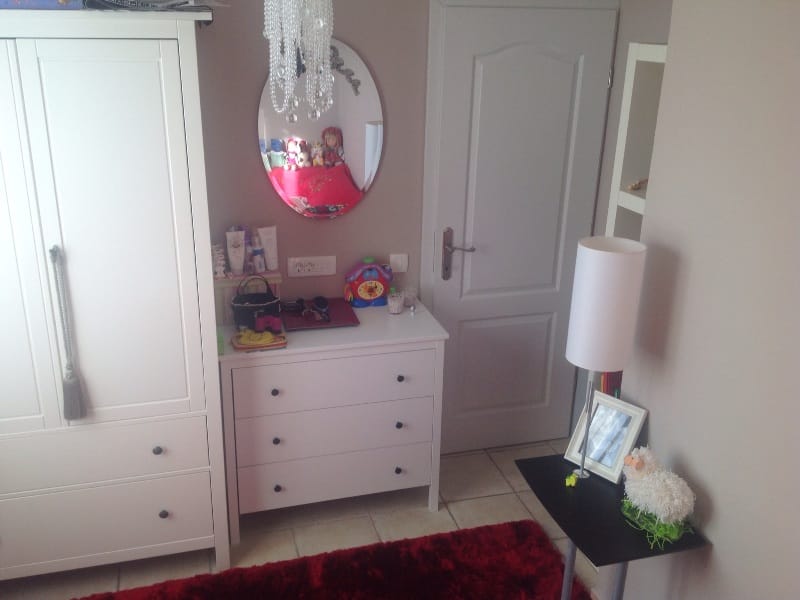 Children’s bedroom interior in a villa in Shushan, Montenegro: white dresser, wardrobe, oval mirror, and red rug.