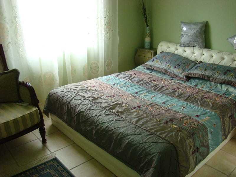 Cozy bedroom with a double bed in a villa in Shushan, Montenegro: bright interior, armchair, and tiled floor.