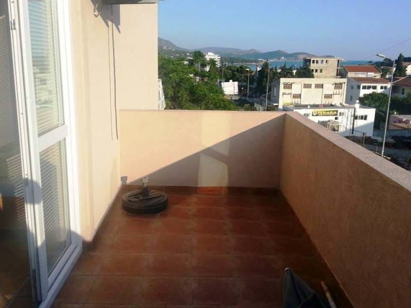 Otvorena terasa s pogledom na more i planine u kući, grad Sutomore, Crna Gora. Popločan pod, izlaz iz panoramskih vrata.