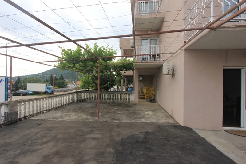 Prostrana terasa sa vinogradnom pergolom i balustradom uz kuću u Sutomoru, Crna Gora, pogled na planine i ulicu.