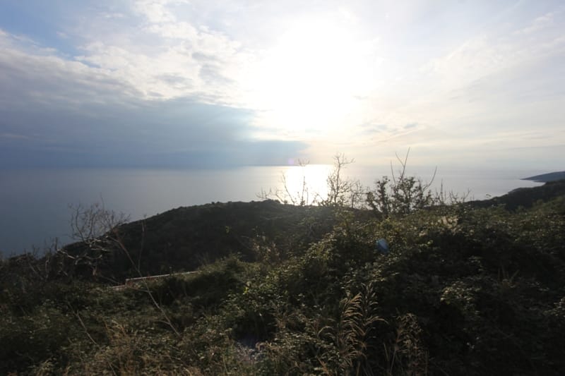 Panoramski pogled na Jadransko more sa zemljišta u Budvi, Crna Gora, u pozadini brežuljkastog pejzaža.