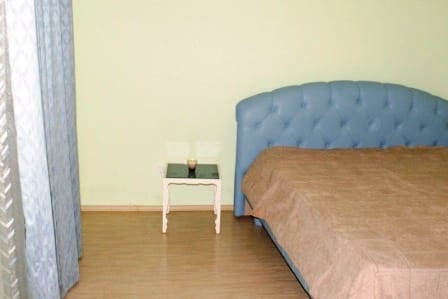 Spavaća soba u kući u Igalu, Crna Gora: bračni krevet sa plavim mekim uzglavljem i noćni stočić.