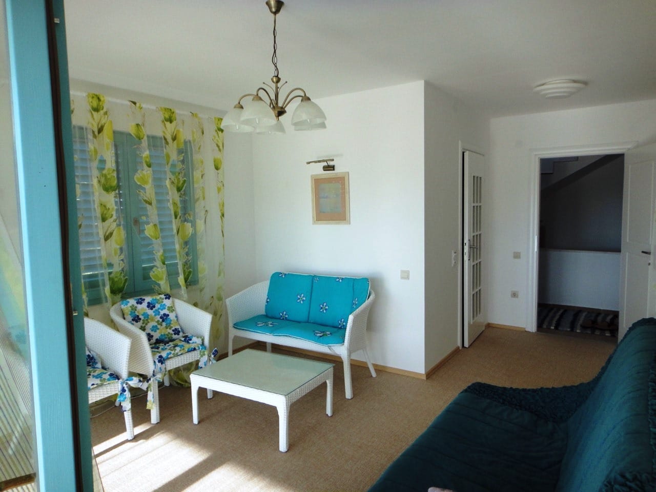 Светлая гостиная в доме в Добрых Водах, Черногория: плетеная мебель, журнальный столик и выход в коридор.