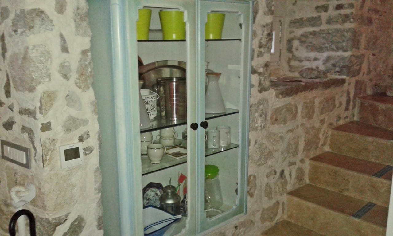 Vintage-Buffet im Wohnzimmer einer Villa in Perast, Montenegro: Steinverkleidung der Wände und Treppe im Innenraum des Hauses.