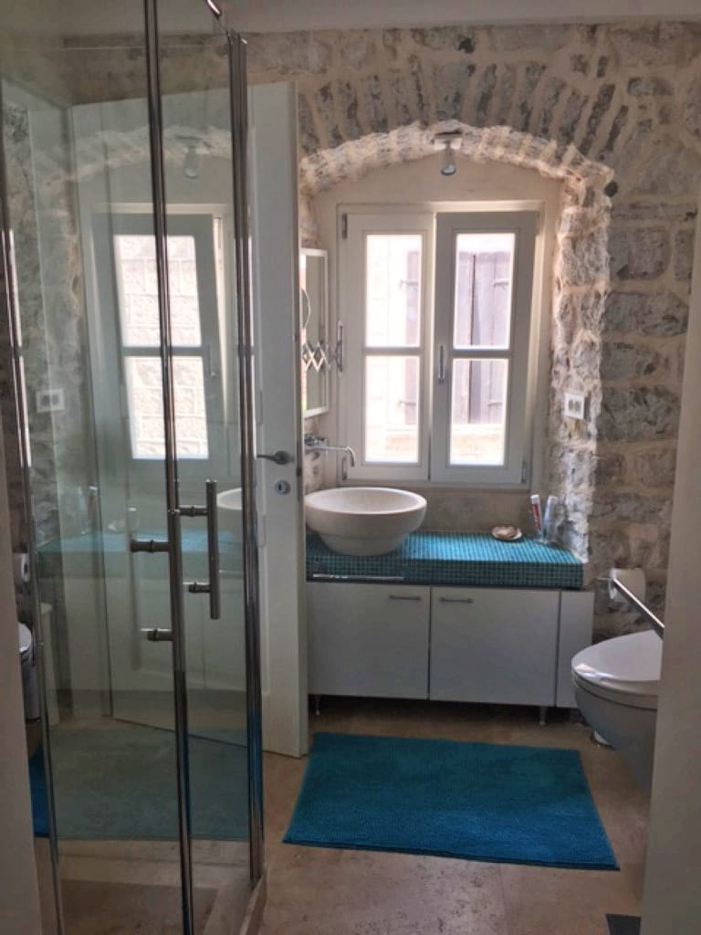 Badezimmer mit Natursteinverkleidung in einer Villa in Perast, Montenegro: Duschkabine und stilvolles Waschbecken.