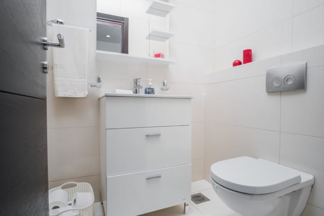 Savremeno kupatilo sa belim nameštajem i visećom WC šoljom u stanu u Budvi, Crna Gora.