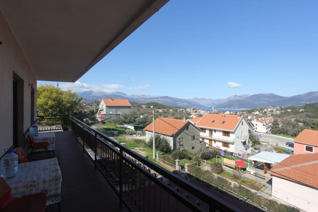 Spacieux balcon de la maison à Radovici, Monténégro, avec vue panoramique sur les montagnes, la mer et les toits en tuiles du village.