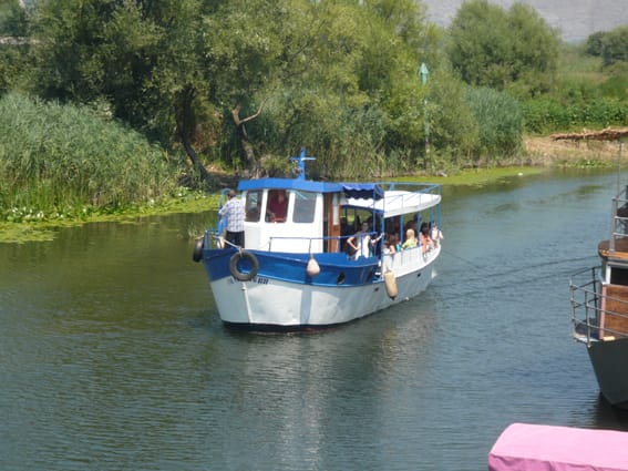 Ausflugsboot mit Touristen auf dem Fluss in Virpazar, Skutarisee, Montenegro, Blick auf das Restaurantgeschäft.
