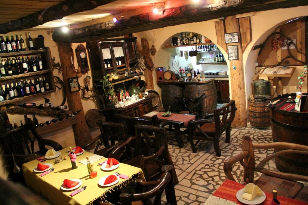 Innenraum eines traditionellen Weinkeller-Restaurants in Virpazar, Montenegro: Holzmöbel, Weinfässer und Regale.
