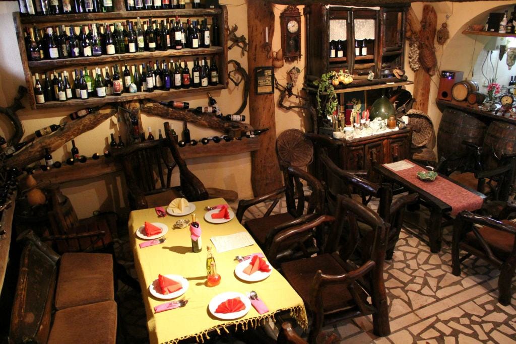 Innenraum eines traditionellen Weinrestaurants in Virpazar, Montenegro: Holzmöbel, Weinregale und Steinboden.