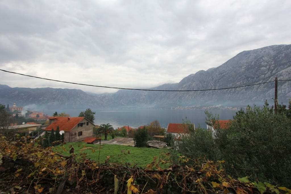 Panoramiczny widok na Zatokę Kotorską i góry z domu w Prčanj, Czarnogóra: dachy z dachówki, zieleń i morski krajobraz.