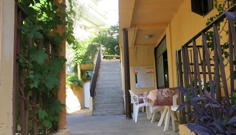 Ulaz u mini-hotel u Rafailovićima, Crna Gora: kameno stepenište, terasa sa stolovima i zelenilo.