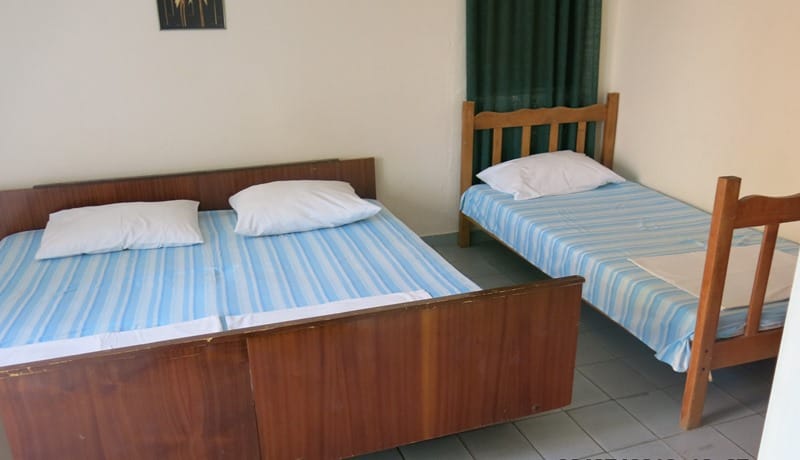 Spavaća soba u mini-hotelu Rafailovići, Crna Gora: bračni i jednokrevetni krevet sa drvenim okvirima i svetlom posteljinom.