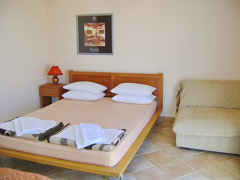 Spavaća soba u hotelu Sutomore, Crna Gora: bračni krevet, fotelja, noćni stočić i pod od pločica.