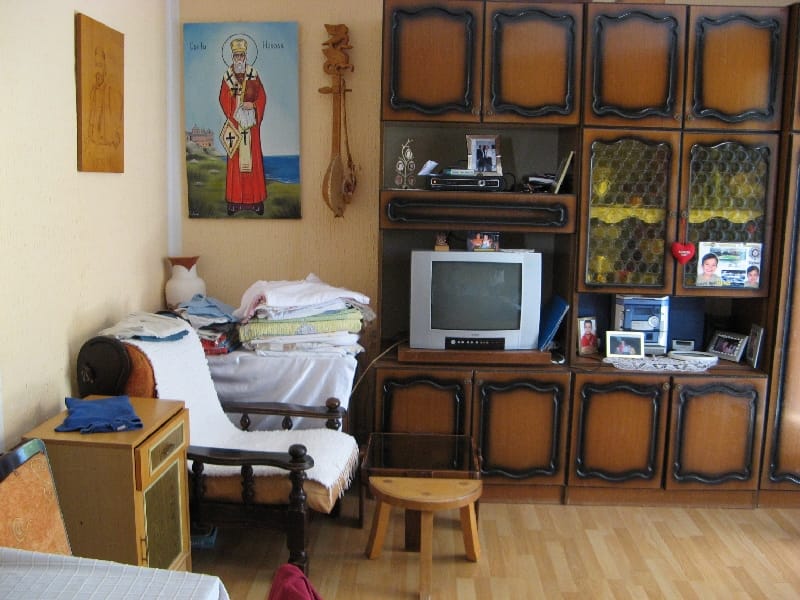 Dnevna soba u kući u Šušnju, Crna Gora: klasična drvena vitrina, fotelja, televizor i ikona na zidu.