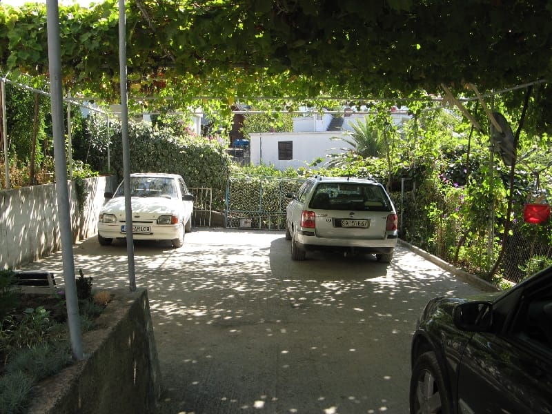 Privatni parking u dvorištu kuće u Šušnju, Crna Gora, sa nadstrešnicom od vinove loze i mestima za nekoliko automobila.