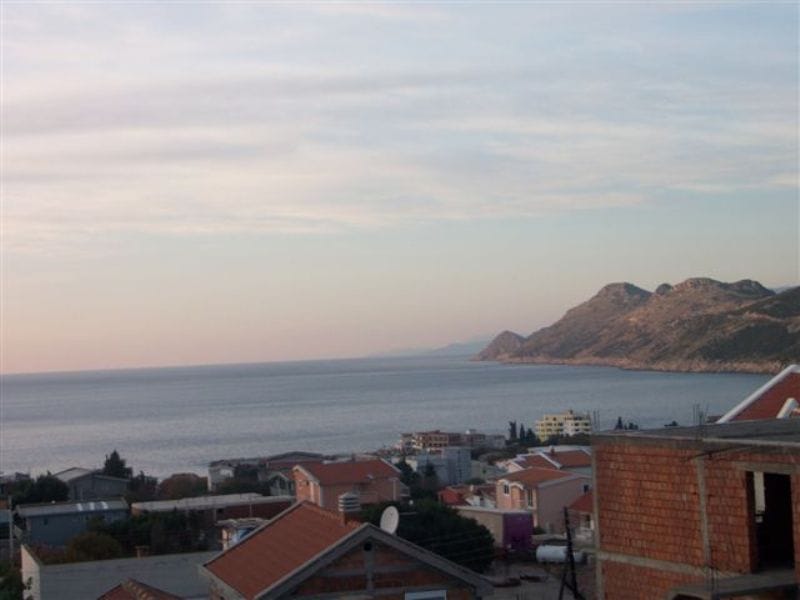 Панорамный вид на море и горы из квартиры в поселке Добрые Воды, Черногория, с обзором на прибрежную застройку.