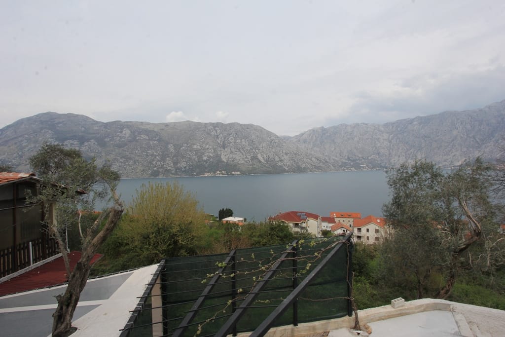 Panoramski pogled na Bokokotorski zaliv i planine sa terase kuće u Prčanju, Crna Gora, sa elementima pejzaža i zelenila.