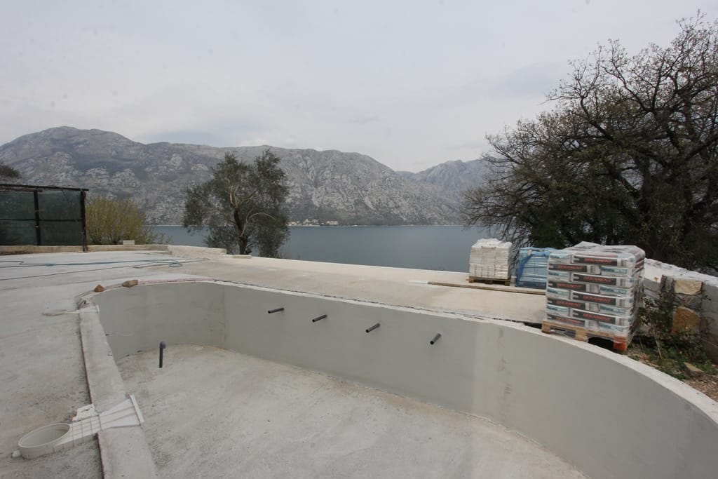 Bazen u izgradnji na vili u Prčanju, Crna Gora, sa panoramskim pogledom na Bokokotorski zaliv i planine.