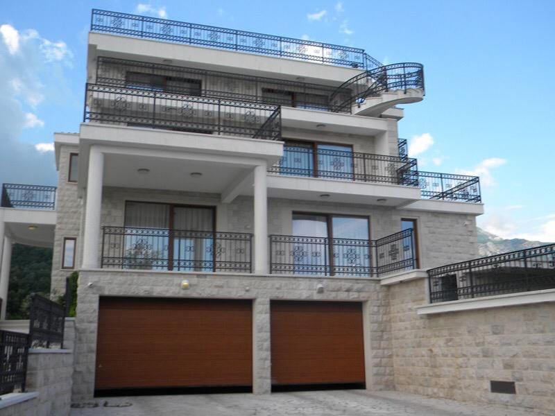 Trzypiętrowa willa w Herceg Novi, Czarnogóra: kamienna elewacja, tarasy z kutymi balustradami i garaż na dwa auta.