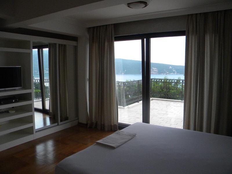 Sypialnia w willi w Herceg Novi, Czarnogóra: widok na morze z tarasu, panoramiczne okna, wbudowana szafa i parkiet.