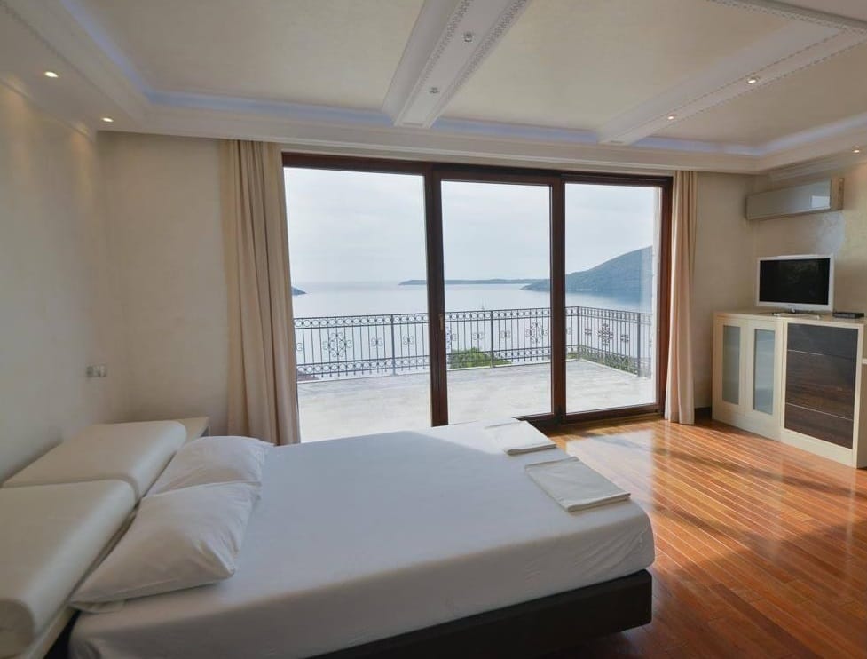 Sypialnia z panoramicznym widokiem na morze i tarasem w willi w Herceg Novi, Czarnogóra: łóżko podwójne i parkiet.
