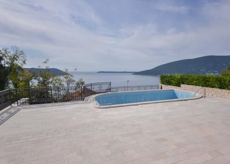 Otwarty basen na tarasie willi w Herceg Novi, Czarnogóra, z panoramicznym widokiem na Morze Adriatyckie i góry.