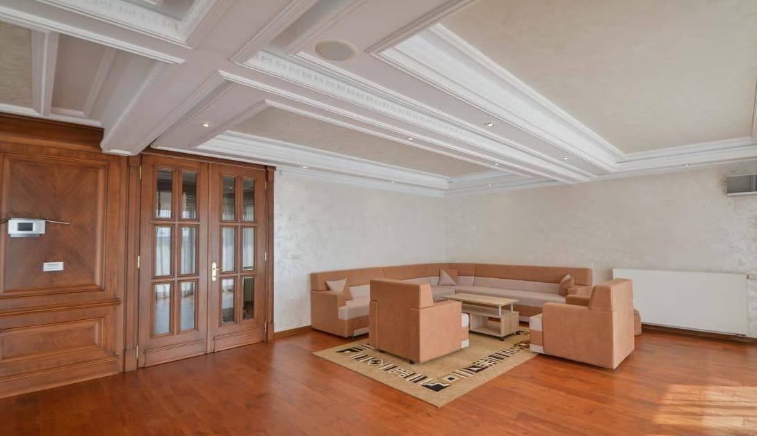 Przestronny salon w willi w Herceg Novi, Czarnogóra: klasyczne wnętrze, drewniane drzwi i parkiet.