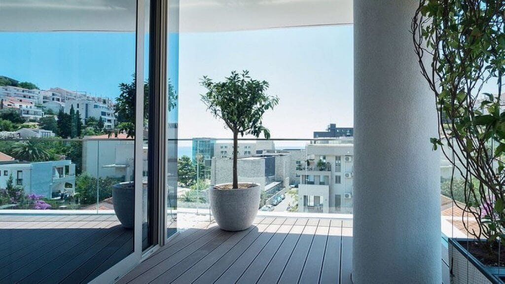 Prostran balkon sa terasnom daskom i pogledom na more u modernom stanu u Budvi, Crna Gora.