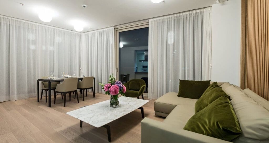 Savremeni dnevni boravak sa trpezarijskim delom u stanu u Budvi, Crna Gora: svetao enterijer, mekana sofa i dekor.