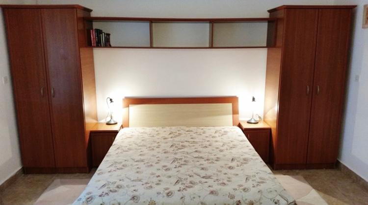 Spavaća soba sa bračnim krevetom i ugradnim ormarima u hotelu, Budva, Crna Gora. Udoban enterijer sa noćnim lampama.