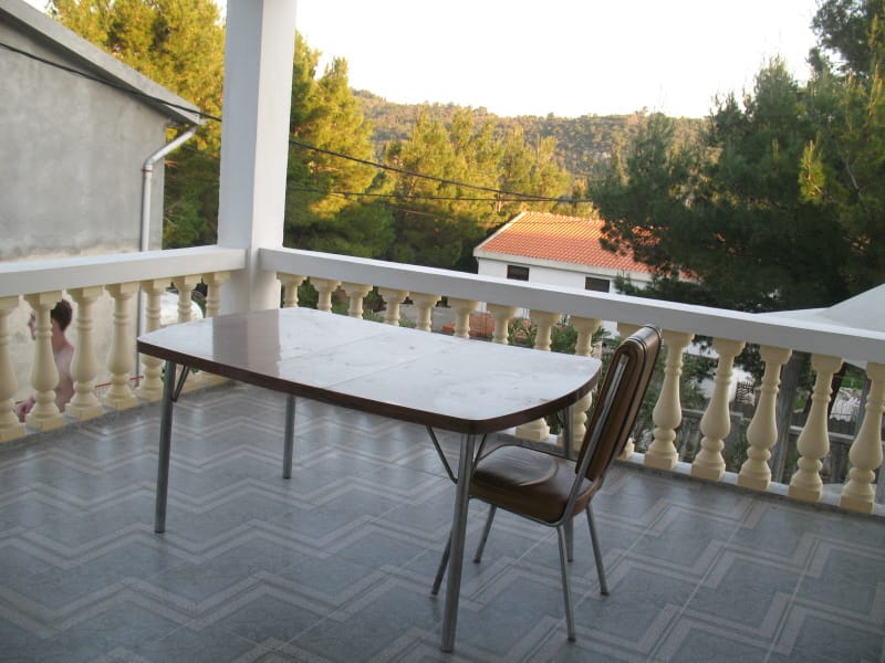 Balkon sa trpezarijskim stolom i pogledom na planine u kući u Sutomoru, Crna Gora. Popločan pod i klasična balustrada.