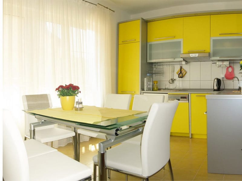 Modern kitchen with a bright yellow cabinet set and dining area in an apartment, Bar, Montenegro.