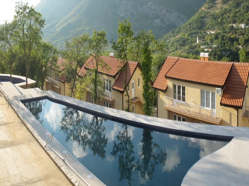 Outdoor pool by villas with mountain views in Bar, Montenegro: modern finishes and panoramic scenery.