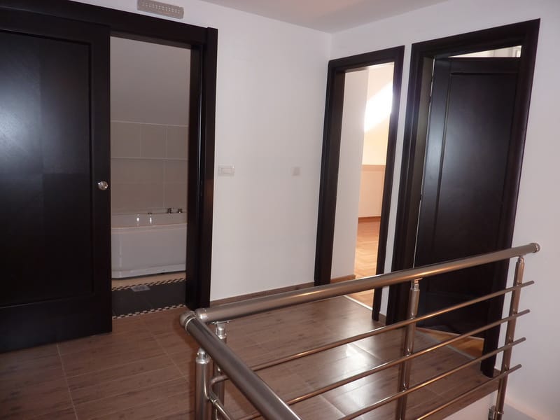 Intérieur d’un appartement à Budva, Monténégro : hall lumineux avec portes intérieures foncées et vue sur la salle de bains.