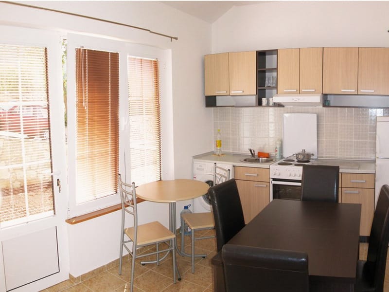 Kitchen-dining room in an apartment in Bar, Montenegro: light-colored cabinetry, dining table, appliances, and panoramic windows.