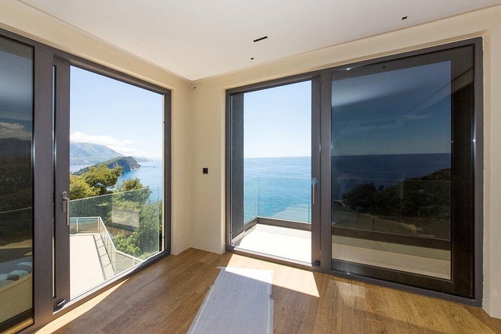 Living room with panoramic windows and sea view in an elite villa in Budva, Montenegro: modern interior, terrace.