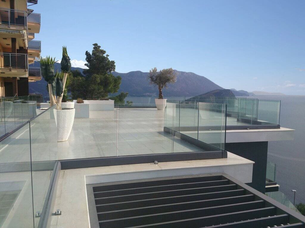 Spacious villa terrace in Budva, Montenegro, with glass railing, floor tiles, and panoramic sea views.