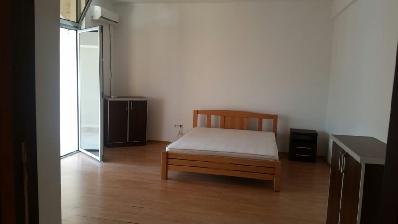 Svetla spavaća soba sa drvenim krevetom i izlazom na balkon u stanu, grad Budva, Crna Gora.