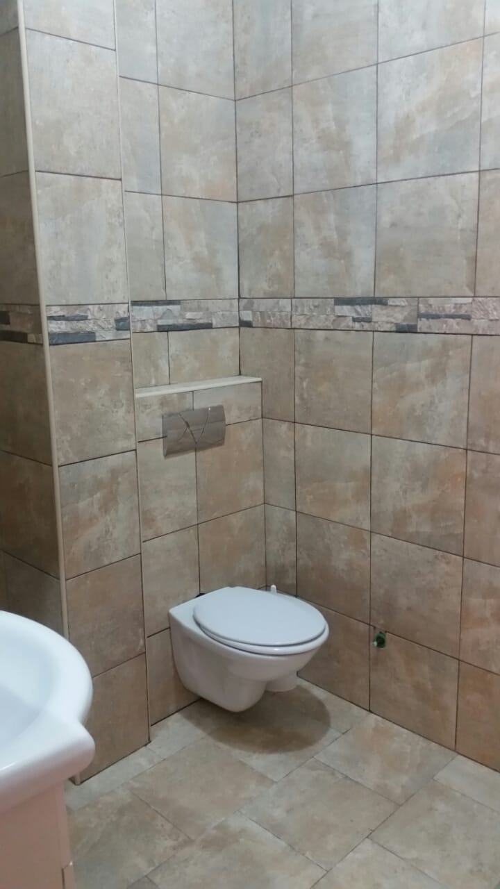 Savremeno kupatilo u stanu u Budvi, Crna Gora: viseća WC šolja i obloga od bež pločica u imitaciji kamena.