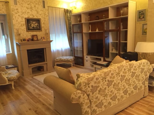 Уютная гостиная с камином и мягкой мебелью в доме, Зеленика, Черногория. Классический интерьер с деревянным полом.